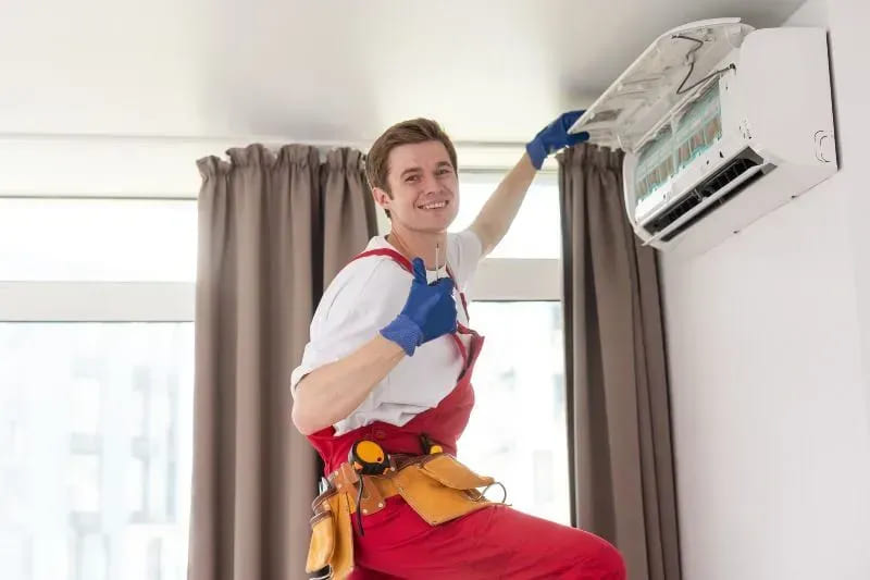technician maintaining modern air conditioner