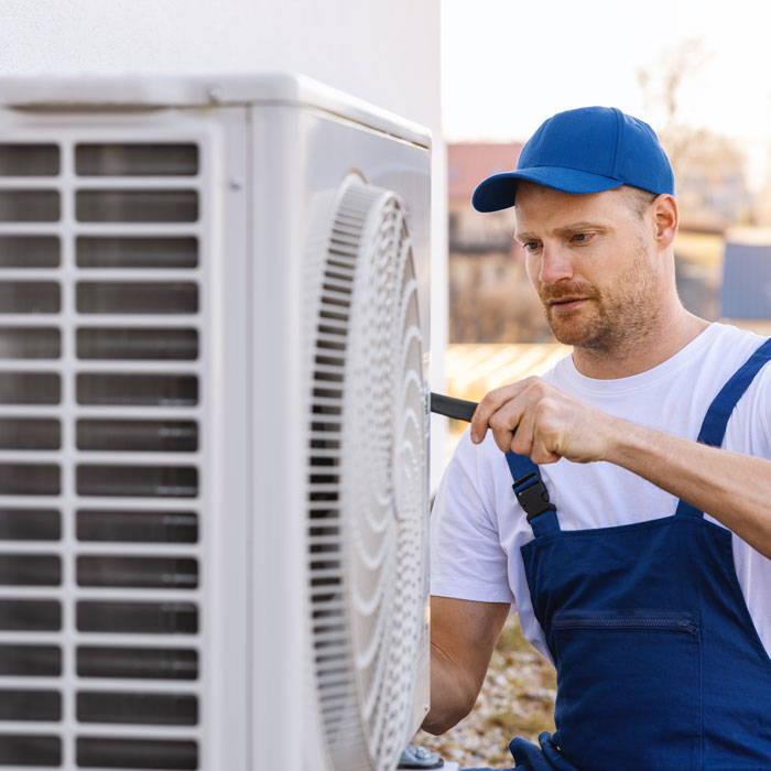man inspecting heat pump