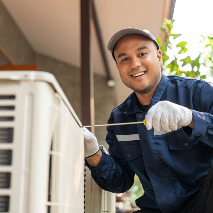 technician smiling while using tool on home hvac unit