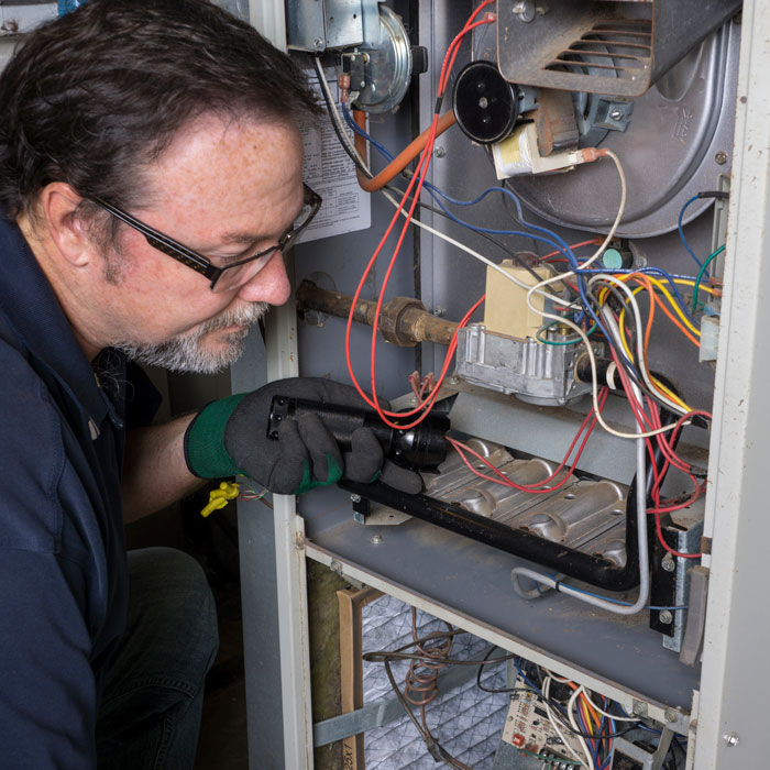 technician looking at internals of home furnace