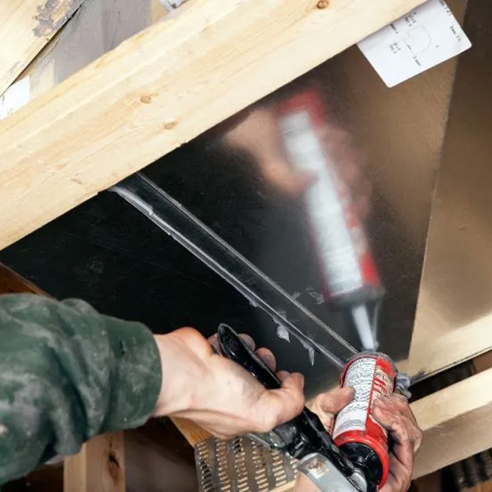 man using silicon to seal air duct