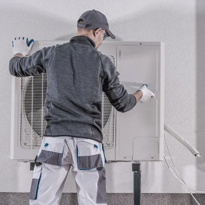 man inspecting heat pump