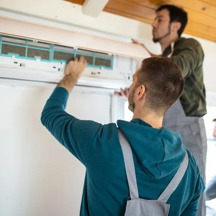 Two technicians performing maintenance on an AC unit setting in Volusia and Flagler Counties, FL.