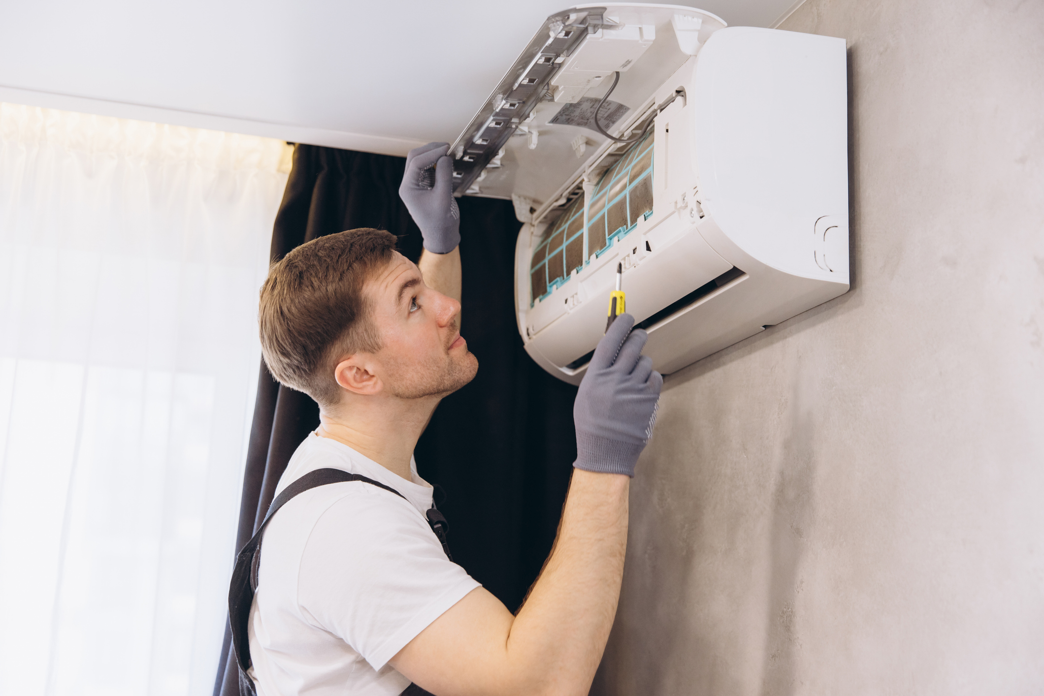 Technician servicing a wall-mounted AC for better airflow in a home in Volusia and Flagler Counties