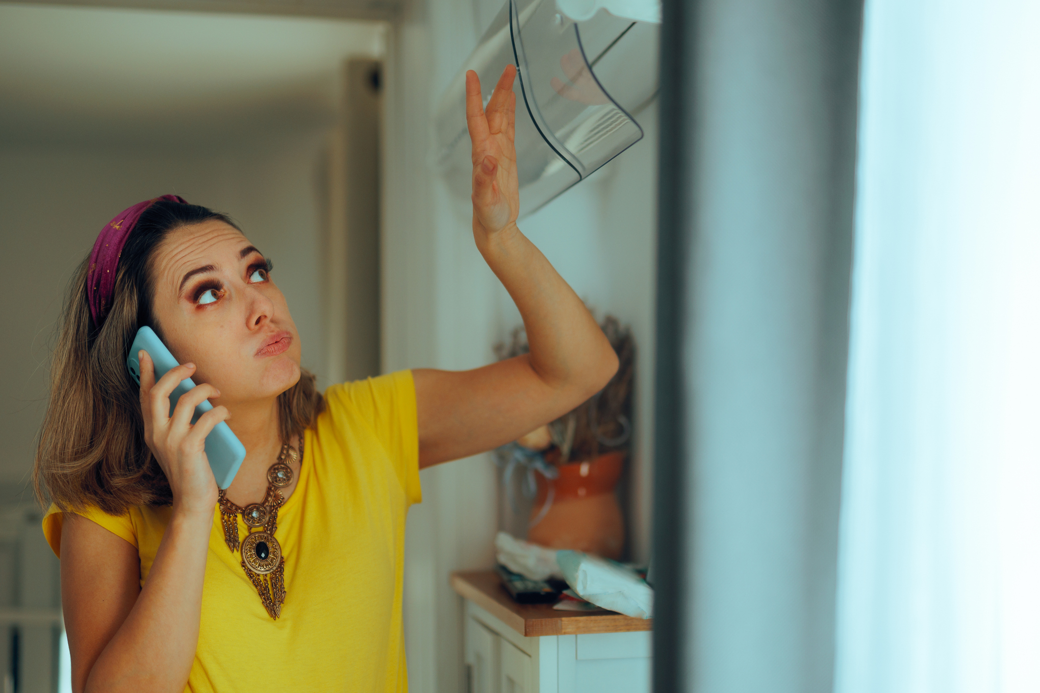 Woman checks open AC unit over uneven cooling at home in Volusia and Flagler Counties